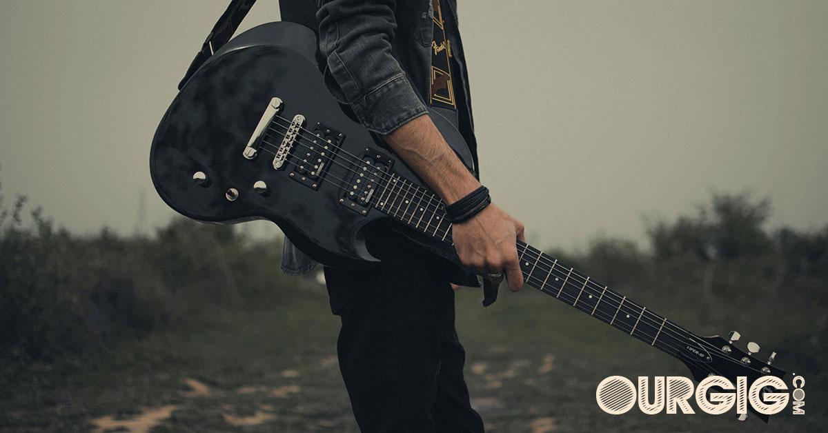 man holding his guitar in the country