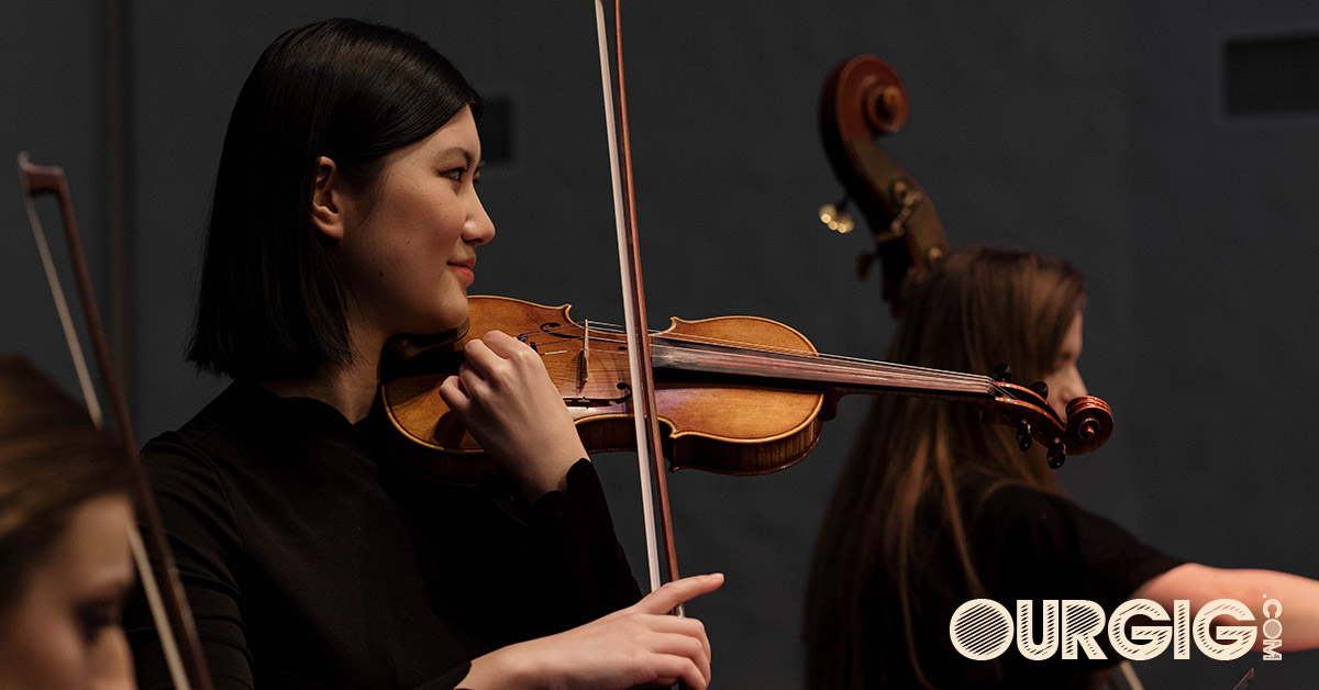 woman playing violin in concert ourgig.com