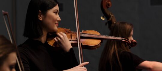 woman playing violin in orchestra