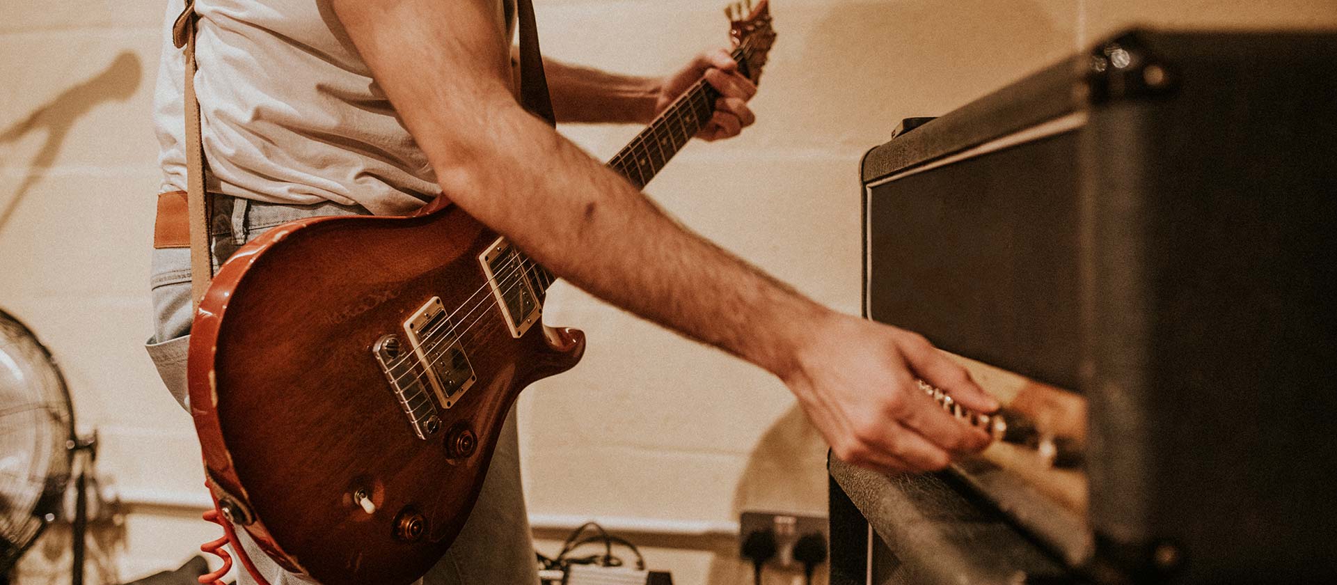 man adjusting amplifier sound for his guitar