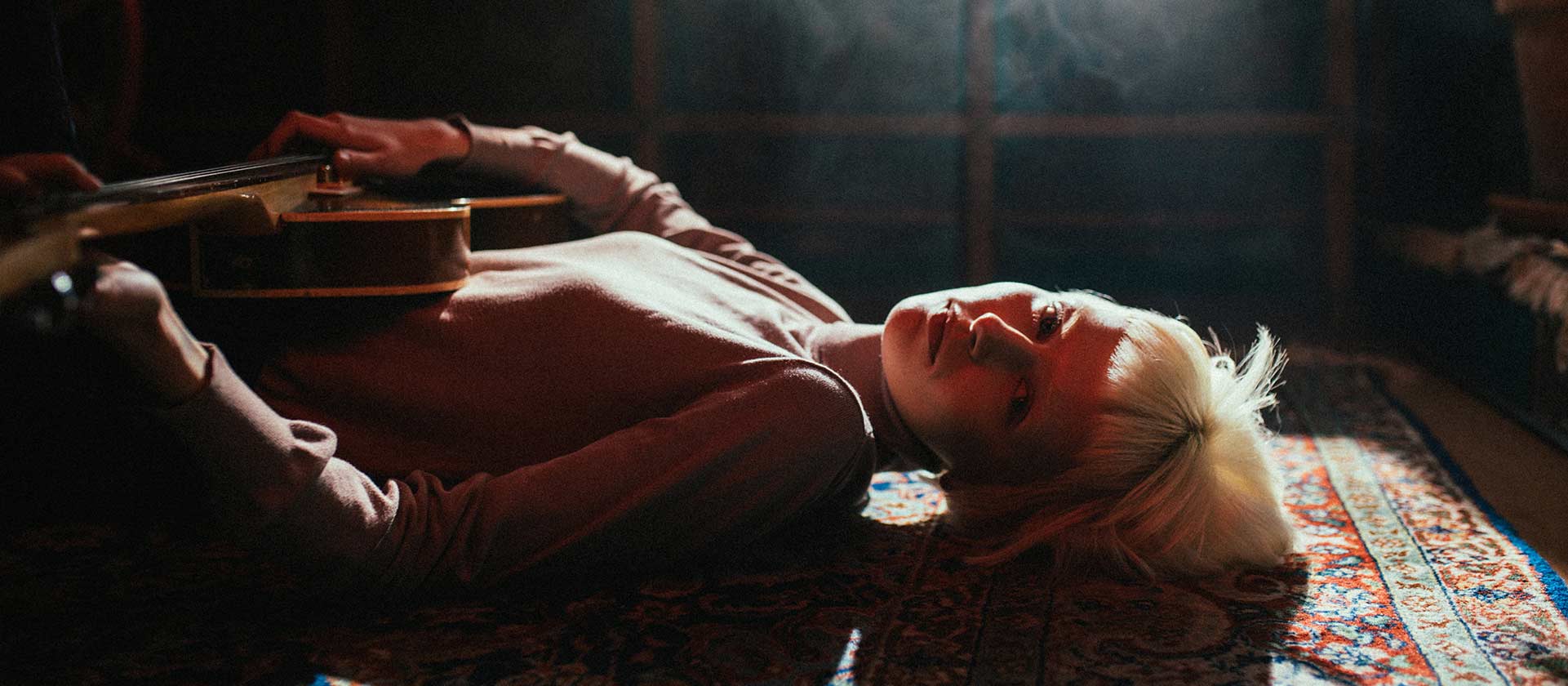 female artist laying on floor holding a guitar