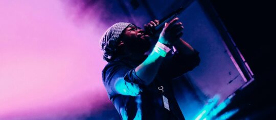 male artist performing on colorfully lit state