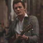 male artist playing guitar in city center