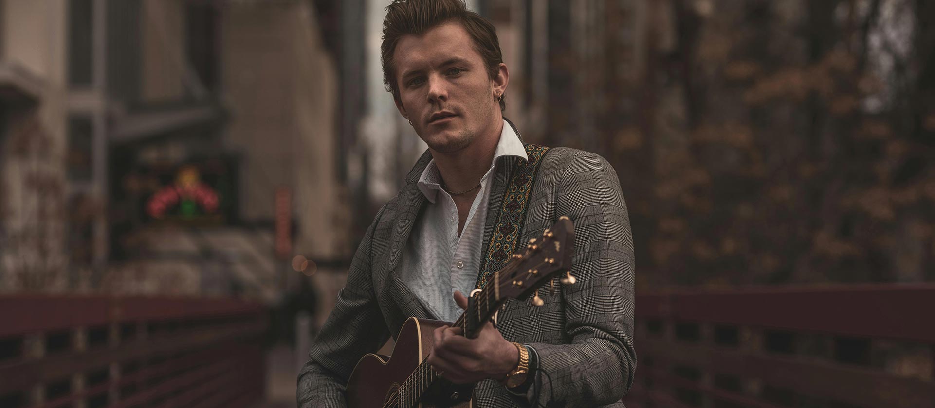 male artist playing guitar in city center