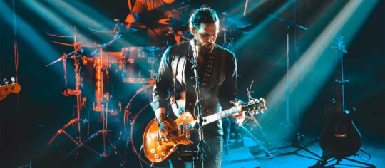 male artist playing guitar in concert