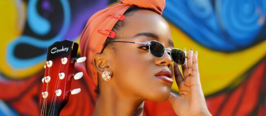 woman musician holding guitar in colorful photo
