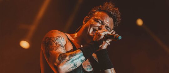 male vocalist with tattoos on stage