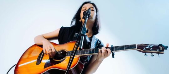 female vocalist playing guitar