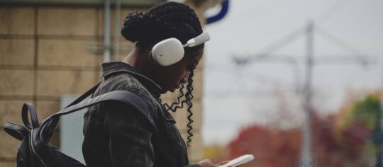 girl wearing earphones while waiting for train